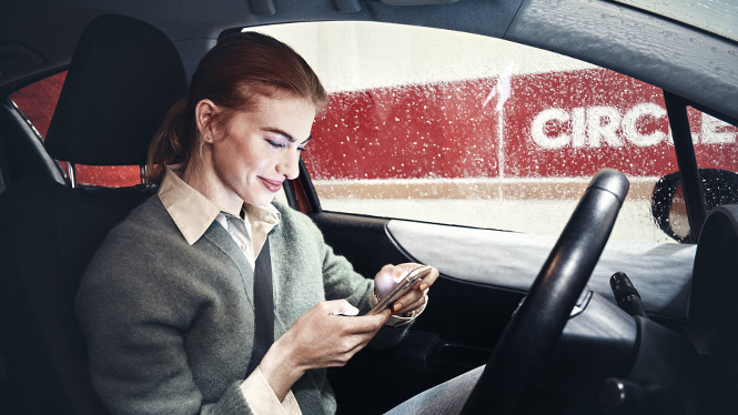 Kvinde i vaskehal, som sidder med sin mobil