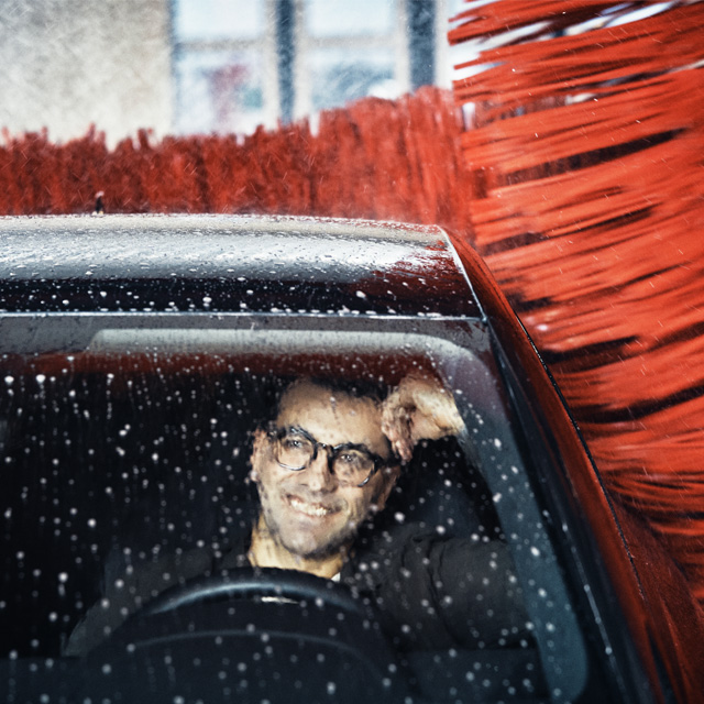 mand sidder i sin bil, mens den vaskes i vaskehal