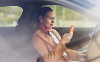 Woman checking her phone while stationary in her car