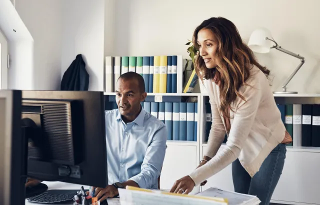 Woman and man excitedly looking at the computer monitor together in an office